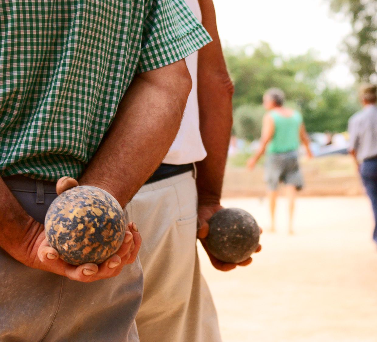 Two players holding bocce behind their backs